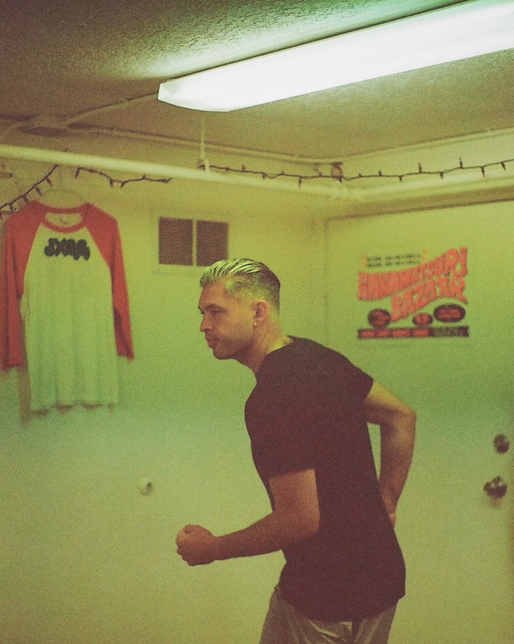 Isaac Hernandez in a black tee, shot on film in a green-lit room.