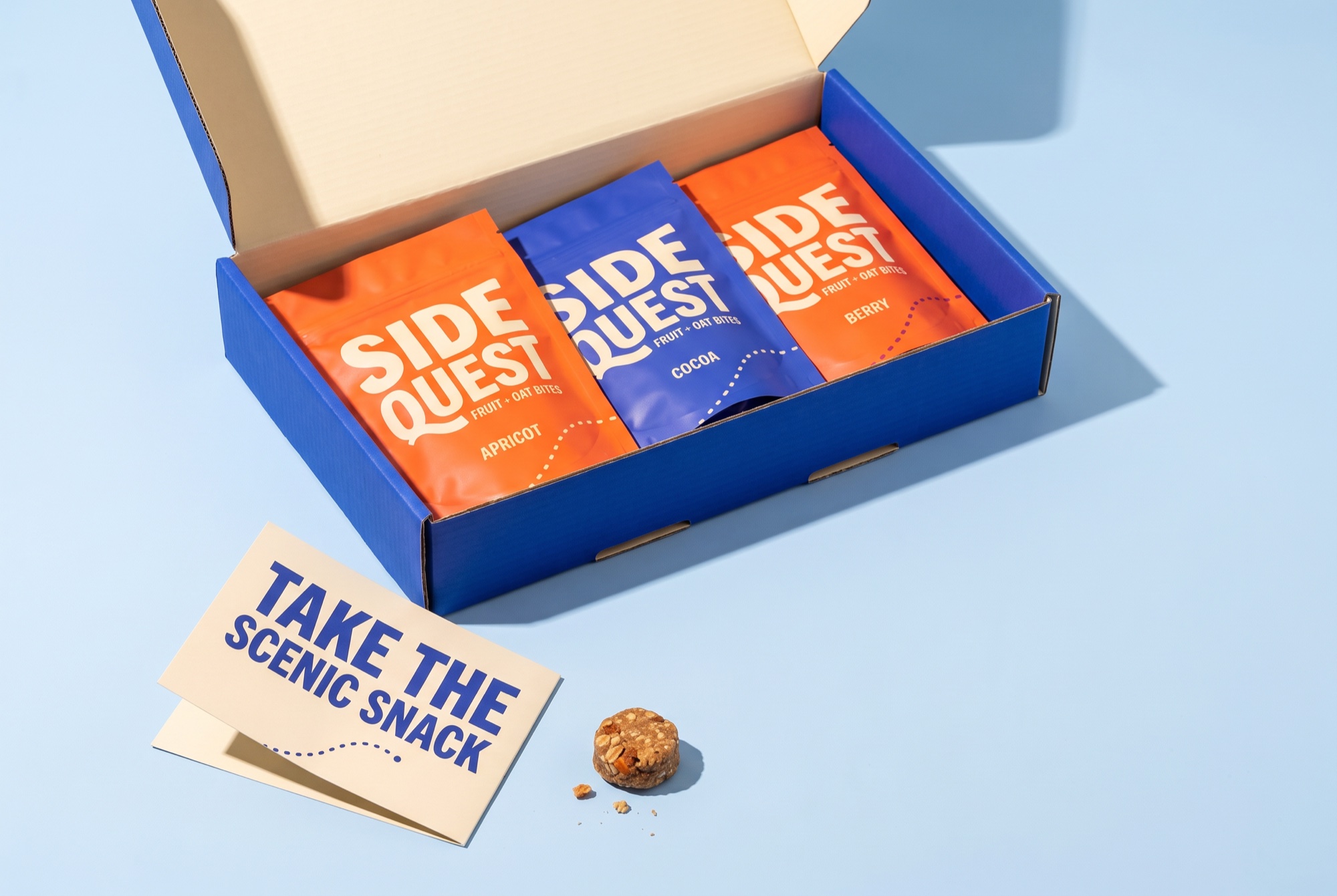 An open SIDEQUEST PR gift box with snack pouches and a campaign insert.